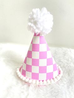 "These MINI party hats are the perfect accessory for your little one's big day or photo session. All hats are made to order. Each hat along with the bows and embellishments are carefully handcrafted so each hat is unique and will vary slightly because of this.  PLEASE LEAVE YOUR EVENT DATE AT CHECKOUT. PARTY HAT FEATURES: -Mini Party Hat (approximately 3\"x5\")  -Pink checker fabric-covered hat designed with a custom template -Optional: add a white glitter number  -White mini pom pom trim and wh Fun Costume Hats For Birthday, Fun Birthday Party Hat Supplies, Fun Adjustable Birthday Party Supplies, Pink Novelty Mini Hat For Birthday, Novelty Pink Mini Hat For Birthday, Fun Pink Birthday Hat, Whimsical White Mini Hat For Gifts, Whimsical White Mini Hat As Gift, Playful White Party Supplies