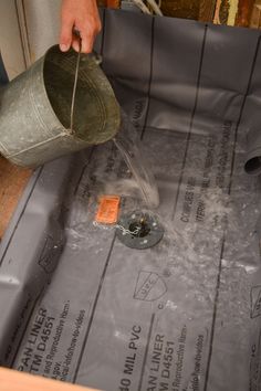 a man pours water into a hole in the floor that is being built for a house