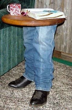 a person standing with their feet on a table and holding a coffee cup in front of them