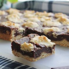 chocolate and marshmallow bars are sitting on a white surface next to a blue checkered napkin