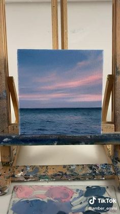 an easel sitting on top of a table next to the ocean