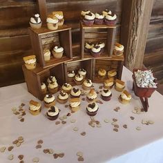 cupcakes are arranged on wooden shelves in front of a white tablecloth with gold confetti