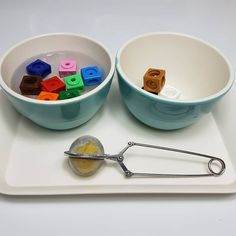 there are two bowls with legos in them and a measuring spoon on the tray