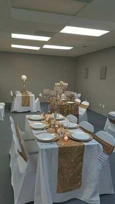 a banquet room set up with white and gold table cloths, silver chairs, and centerpieces