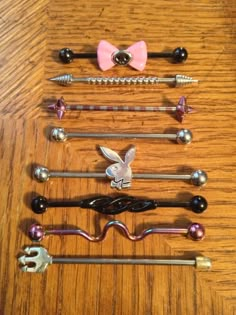 several different types of metal and wood handles on a wooden table, with one pink bow at the top