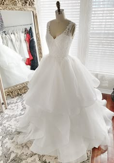 a wedding dress on display in front of a mirror