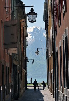 people are walking down an alley way with mountains in the background