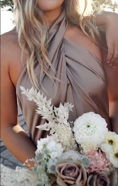 a woman in a brown dress holding a bouquet of white and pink flowers with her arm around her neck