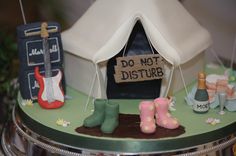 a cake that is decorated to look like a tent with boots on it and a sign saying do not disturb