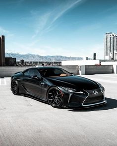 a black sports car is parked in front of some tall buildings on a sunny day