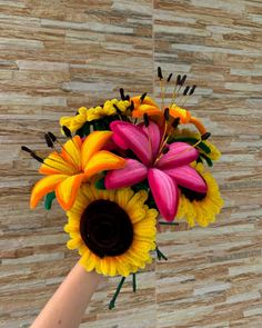 a hand holding a bouquet of colorful flowers