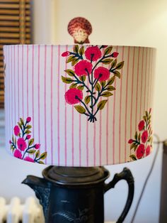 a lamp that is on top of a table with a pink and white striped lampshade