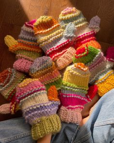 a pile of knitted mittens sitting on top of a person's lap