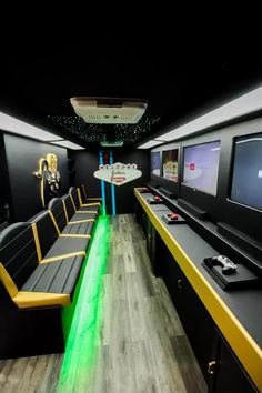 the interior of a bus with black seats and yellow trimmings, television screens on the wall