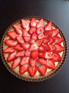 a pie topped with sliced strawberries on top of a table