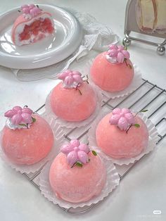 four pink cupcakes sitting on top of a cooling rack next to a slice of cake