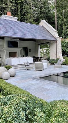 an outdoor living area with a pool and patio furniture in the background, surrounded by greenery