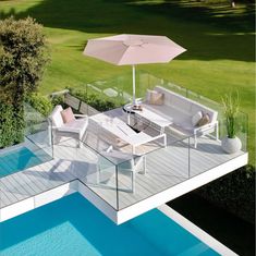 a patio with an umbrella over it next to a swimming pool in the middle of a grassy area