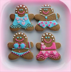 four decorated gingerbreads on a white plate with pink and blue trim around the edges