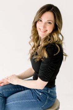 a woman sitting on top of a stool smiling