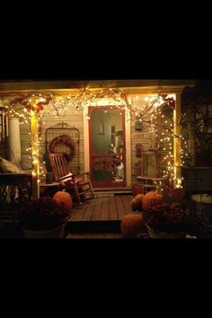 a porch decorated for halloween with pumpkins and lights