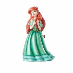 the little mermaid figurine is wearing a green dress