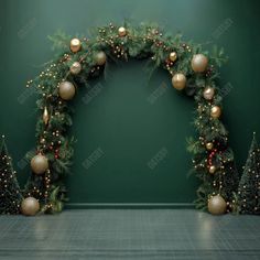 an arch decorated with christmas balls and garland on a green wall in front of a fireplace