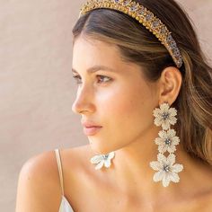 a woman wearing a tiara and earrings with flowers on the top of her head