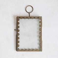 an old photo frame hanging on a wall with a key chain attached to it and a ring in the middle