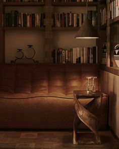 a brown leather couch sitting in front of a bookshelf