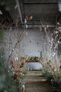 an outdoor ceremony with flowers and branches in the foreground, surrounded by greenery