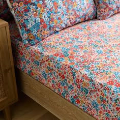 a bed with colorful floral sheets and pillows