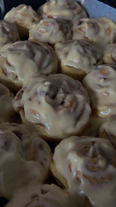 cinnamon rolls with icing sitting on top of a pan