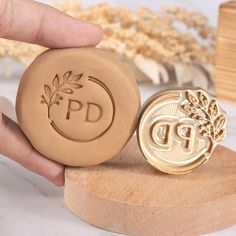 a person holding a waxed stamp next to a wooden block with the word pd on it