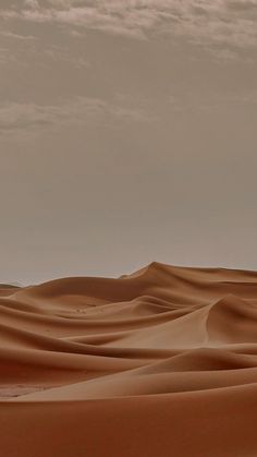 the desert is filled with sand dunes under a cloudy sky