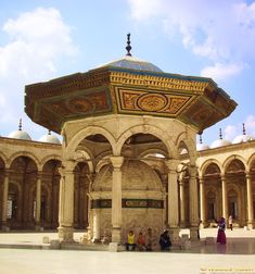 people are sitting on the ground in front of an ornate building with arches and pillars