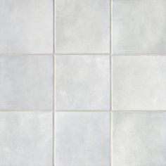 a white tile wall with several different shades of gray and white tiles on it,