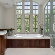 a large white bath tub sitting in a bathroom next to a walk - in shower