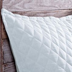 a white quilted pillow sitting on top of a wooden headboard