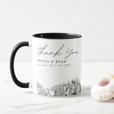 a black and white coffee mug next to a donut