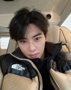 a young man sitting in the back seat of a car wearing a puffy jacket