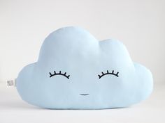 a cloud shaped pillow with eyelashes on it's face and eyes drawn in the clouds