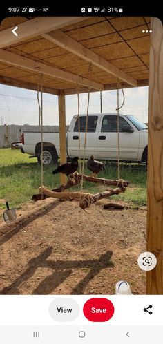 a white truck parked under a wooden structure with chickens on it's back legs