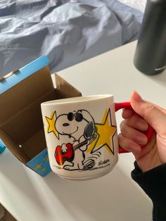 a person holding a coffee cup with a cartoon dog on it and a red handle