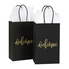 two black and white shopping bags with the word welcome written on each bag in gold foil