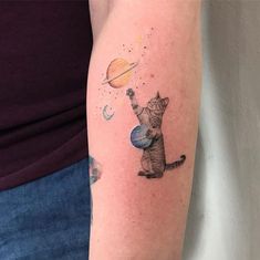 a woman with a tattoo on her arm has a cat and planets in the sky