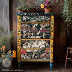 an ornate painted dresser with flowers and potted plants in the background on a wooden floor