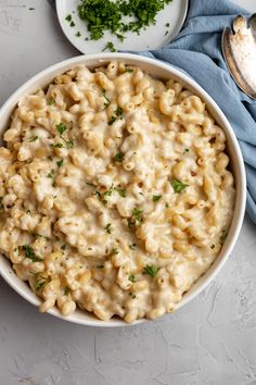 macaroni and cheese with parsley in a white bowl on a blue napkin