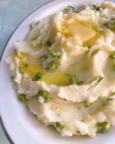 mashed potatoes with butter and green onions on a white plate, ready to be eaten