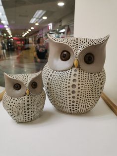 two ceramic owls sitting next to each other on a table